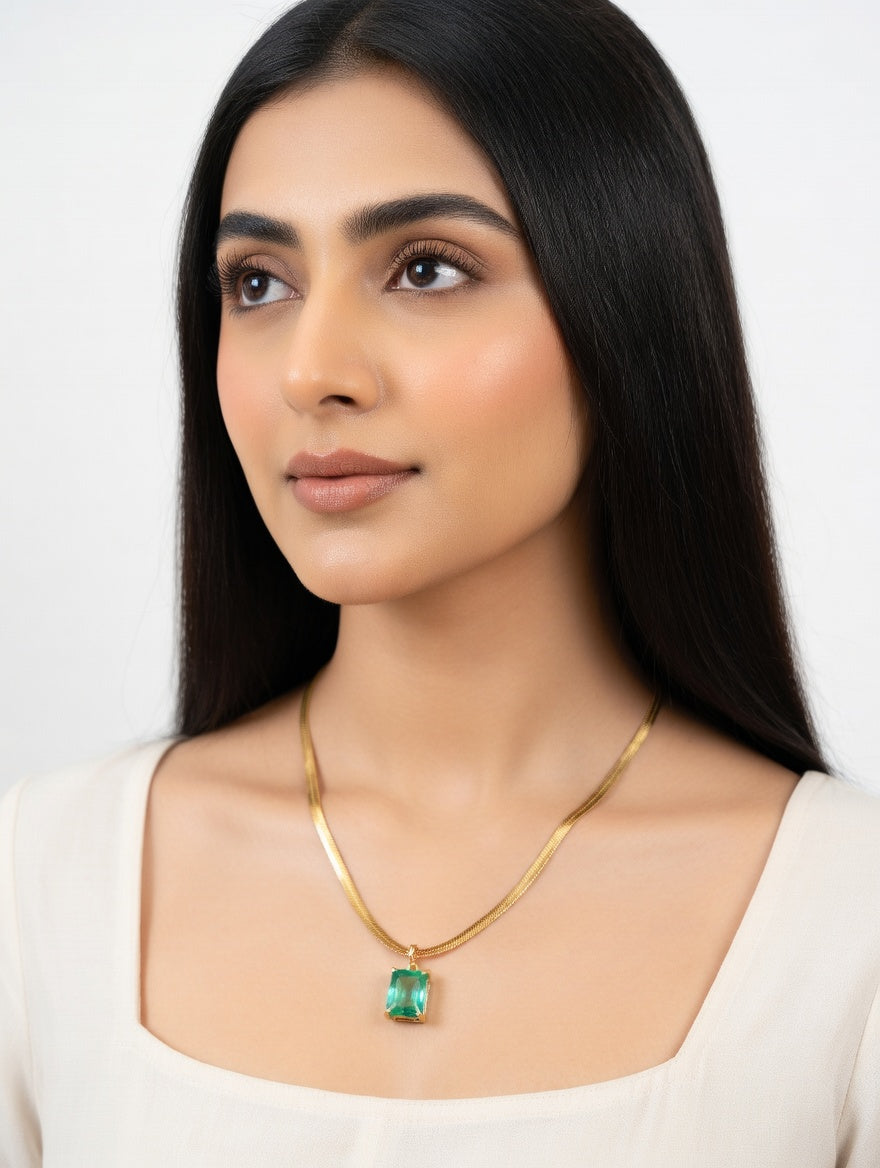 Green emerald necklace from Ashir Studio featuring a delicate silver chain and a vibrant emerald pendant.
