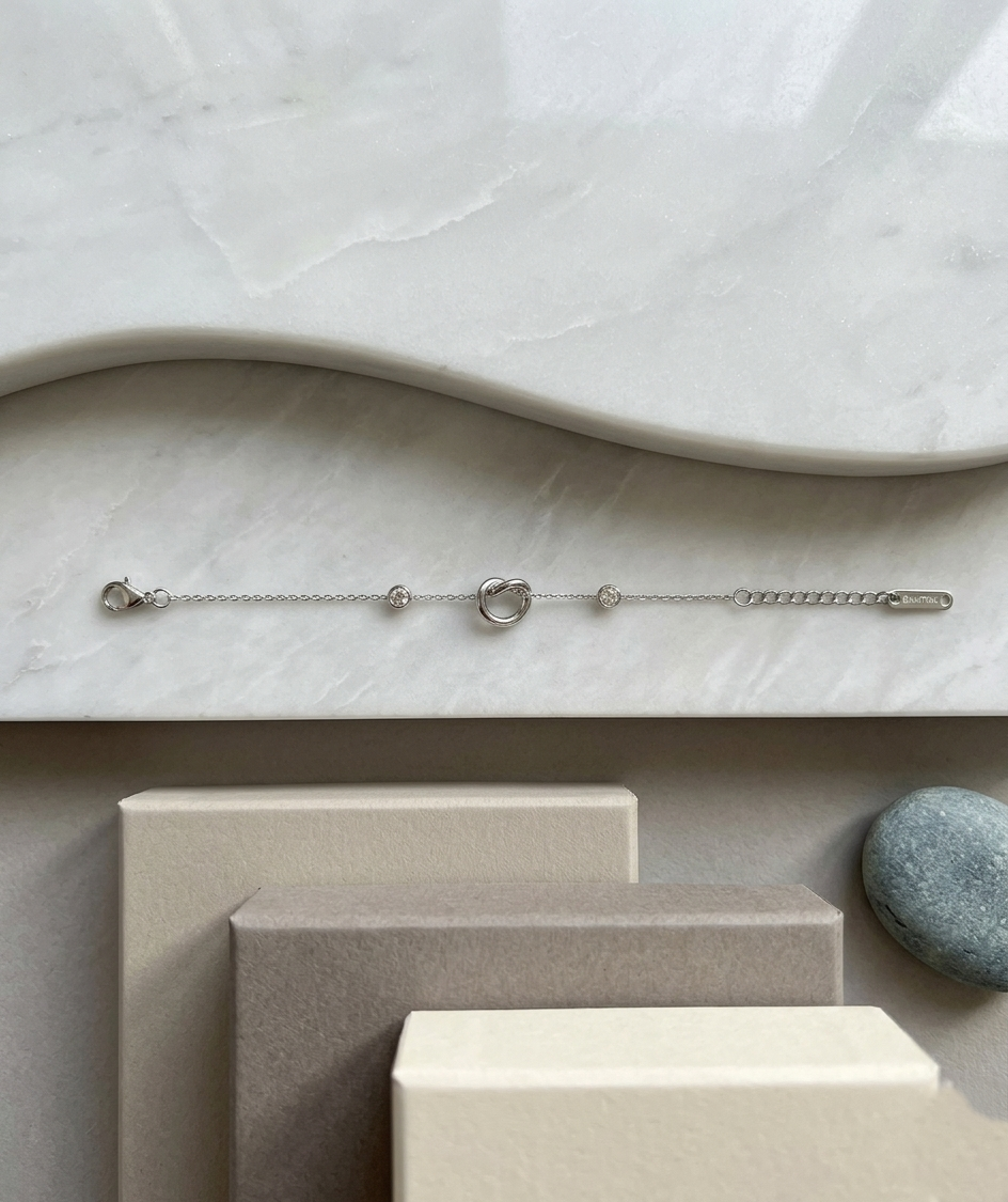 Silver-toned interlock bracelet from Ashir Studio, featuring delicate jewelry design with interconnected links.