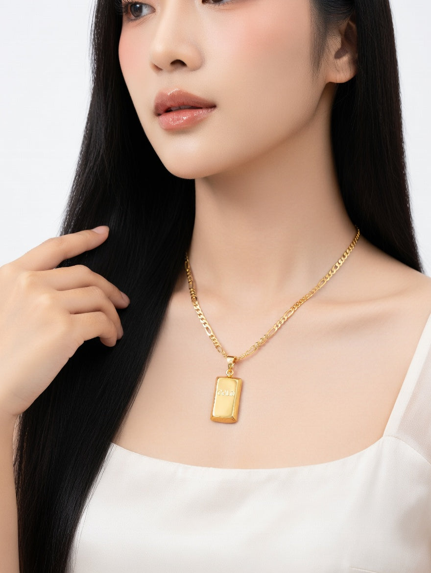 Gold bar pendant and Figaro chain necklace by Ashir Studio, featuring a sleek gold jewelry design with intricate chain links.